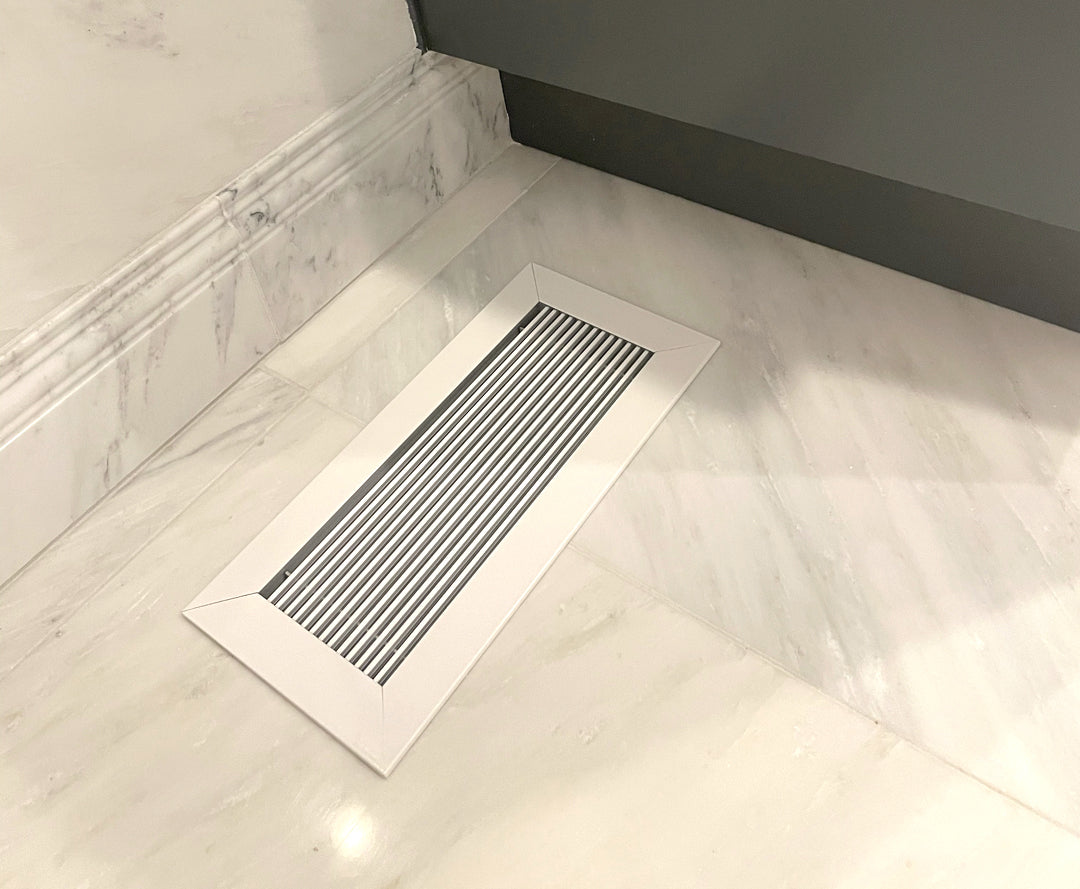 https://www.kulgrilles.com/cdn/shop/products/floor-vent-covers-glacier-frost-on-bathroom-white-marble-floor-beside-grey-cabinet-by-kulgrilles_2.jpg?v=1696353826